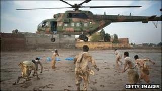 Local residents scramble to recover water bottles dropped from a Pakistan Air force helicopter