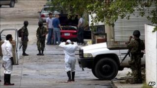 Mortuary workers and armed guards outside funeral home where bodies of 72 murdered Ecuadorean migrants are being kept (26 August 2010)