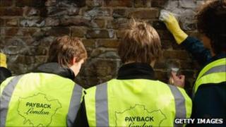 Youths clean graffiti off wall