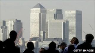 Workers silhouetted in front of the Canary Wharf skyline, London