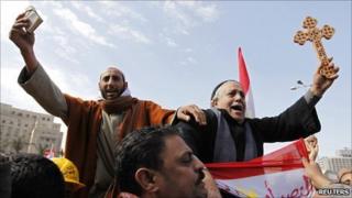 A Muslim holding a Koran (L) and a Coptic Christian holding a cross in Cairo's Tahrir Square - 6 February 2011