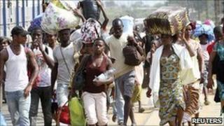 Residents flee with their belongings after clashes between forces loyal to incumbent President Laurent Gbagbo and his rival Alassane Ouattara in Abobo, in Abidjan, 25 February 2011