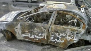 Arabic graffiti on a burnt-out car reads: "Baniyas is the grave of the shabiha."