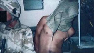A hooded Iraqi detainee