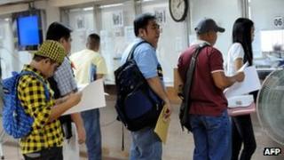 Workers line up at a Philippine Overseas Employment Administration office in Manila on 2 November 2011
