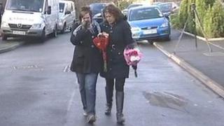 Friends of the family take floral tributes to the scene