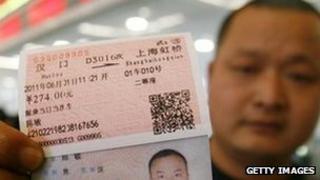 A passenger shows his real-name train ticket at Hankou railway station in Wuhan, central China, 23 May 2011