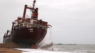 Workers are seen in front of the Maltese-registered cargo ship the TK Bremen, on Kerminihy beach at Erdeven