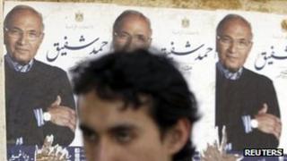 A man walks past posters for Ahmed Shafiq (5 April 2012)