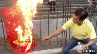 An activist burns a flag of China during a rally in front of the Chinese consular office in Makati's financial district of Manila on 8 May, 2012