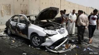 People inspect a car used in a bomb attack in Baghdad (16 June 2012)