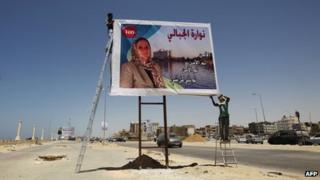 A worker installs a freshly printed election campaign poster of Nawara al-Jabali, a candidate for the upcoming General National Congress election in the eastern city of Benghazi on July 3, 2012.