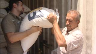 Construction worker Daoud carrying a bag of rice