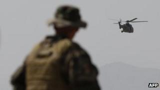 A French Army mentor looks on as a Eurocopter AS 532 Cougar helicopter flies in Kabul on August 12, 2012