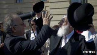 Rabbi Yitzhak Ehrenberg (R) gives his kippah to the head of the Turkish Community in Germany Kenan Kolat during a demonstration in Berlin against the controversial circumcision ruling