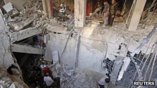 Members of the Free Syrian Army try to recover the body of their comrade from the rubble of a building destroyed by a jet strike in Aleppo on 9 September 2012