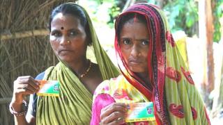 Two women in Samastipur district showing off their health insurance smart cards.