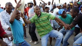 Striking miners dance and cheer after they were informed of a wage increase offer by Lonmin on 18 September 2012