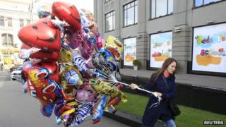 Woman in city street with bunch of balloons