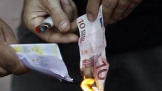 Protestor in Athens burns euro note