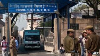 Indian policemen stand guard as an ambulance leaves the main entrance of Tihar Jail in New Delhi on March 11, 2013.