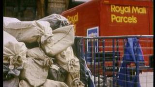A pile of post bags and a Royal Mail delivery lorry.