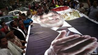 Mohammed Morsi supporters holding a large poster of the ousted president (7 July 2013)