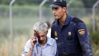 Injured passenger helped away by policeman. 24 July 2013