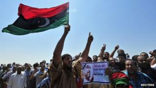 Men hold up a picture of prominent Libyan political activist Abdelsalam al-Mismari during his funeral in Benghazi on 27 July, 2013