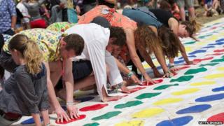 Lots of people playing Twister, with arms and legs crossing over each other
