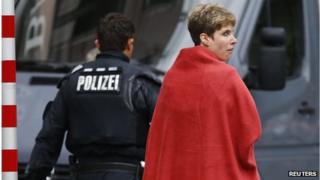 A woman covered in a blanket is escorted from the scene by police after the conclusion of a hostage situation in Ingolstadt (19 August 2013)