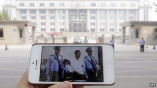 A mobile phone held by the photographer shows a photo from a court's microblog page of disgraced Chinese politician Bo Xilai standing trial in Jinan on 22 August 2013