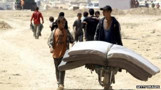Boys carry mattresses through Zaatari refugee camp