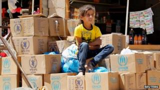 Syrian girl sits on aid boxes at the Al Zaatri refugee camp in Jordan