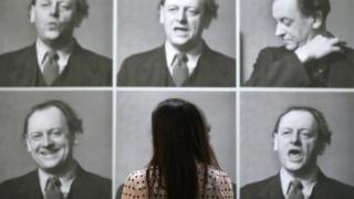 A worker poses next to photographs of Kurt Schwitters