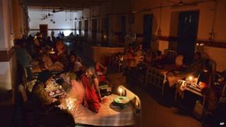 In this Monday, Oct. 7, 2013 photograph, patients light candles and use hand fans to beat humidity at the King George hospital during a power outage at Visakhapatnam, Andhra Pradesh state, India. W