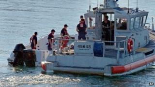 US Coast Guard personnel climb aboard the power boat to examine it