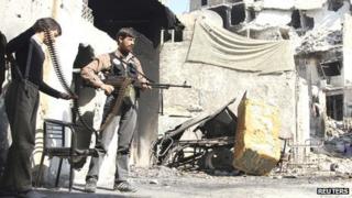 A Free Syrian Army fighter holds his machine gun as a fellow young fighter helps him to carry the ammunition in Old Aleppo, on 4 November 2013