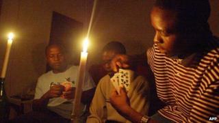 A family plays cards while candles are lit in Harare (21 January 2007)