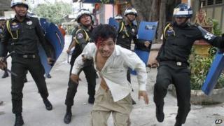 An injured Cambodian worker escapes from riot police in the compound of a Buddhist pagoda in Phnom Penh, Cambodia (12 November 2013)