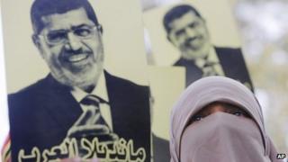 A supporter of Mohammed Morsi in Cairo holds up a picture of him that says: "Mandela of the Arabs" (22 November 2013)