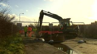 Workman at the road affected by a burst pipe
