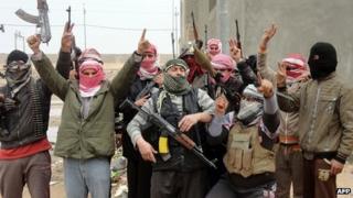 Local tribesmen brandish their weapons as they pose for a photograph in the city of Fallujah