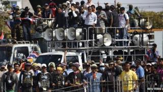 Anti-government protesters lock their arms as they stand at the gates of the Army Club in Bangkok on 28 January 2014.