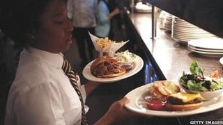 A woman serving burgers in a cafe