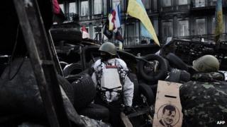 Anti-government protesters stand guard at a road bloc barricade in Kiev