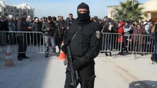 Tunisian Special Forces member stands outside the house which has militants inside.