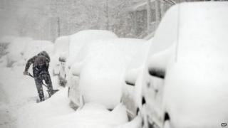 A woman digs her car out of the snow on 15th Street in Bayonne, New Jersey 13 February 2014