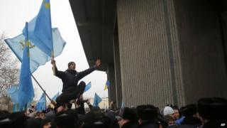 A Crimean Tatar shouts slogans and waves the ethnic flag of the Crimean Tatars during a protest in front of a local government building in Simferopol, Crimea, Ukraine, Wednesday, Feb. 26, 2014.