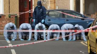 Forensic officers search at the site of a double murder investigation